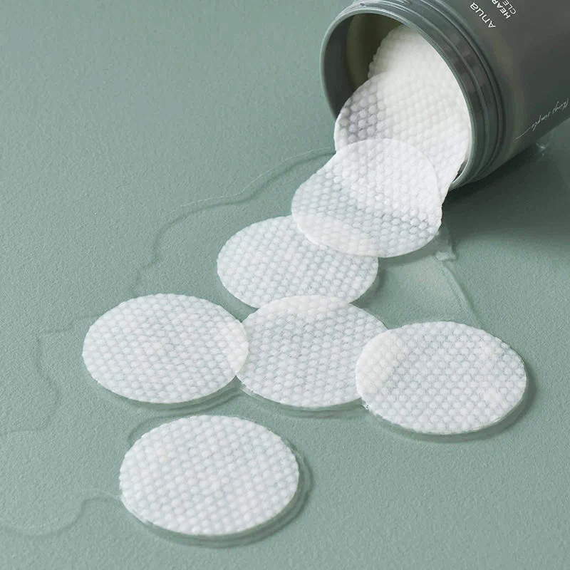 Runde, weiße Pads fallen aus einem umgekippten grünen Behälter, umgeben von etwas Flüssigkeit.