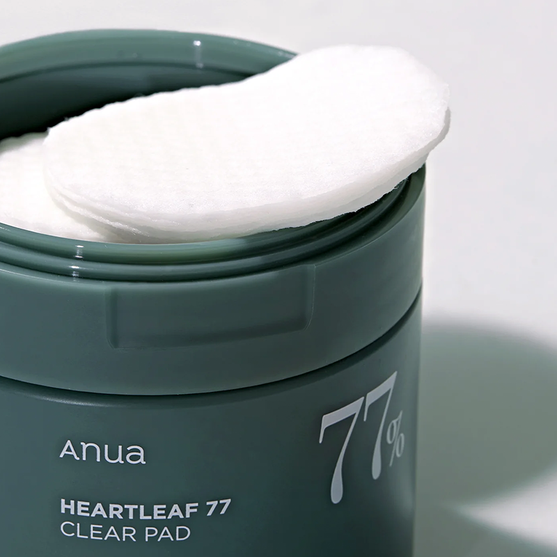 Grüner Behälter mit „Heartleaf 77 Clear Pad“ geöffnet. Auf dem Rand liegt ein Stapel weißer, runder Pads.
