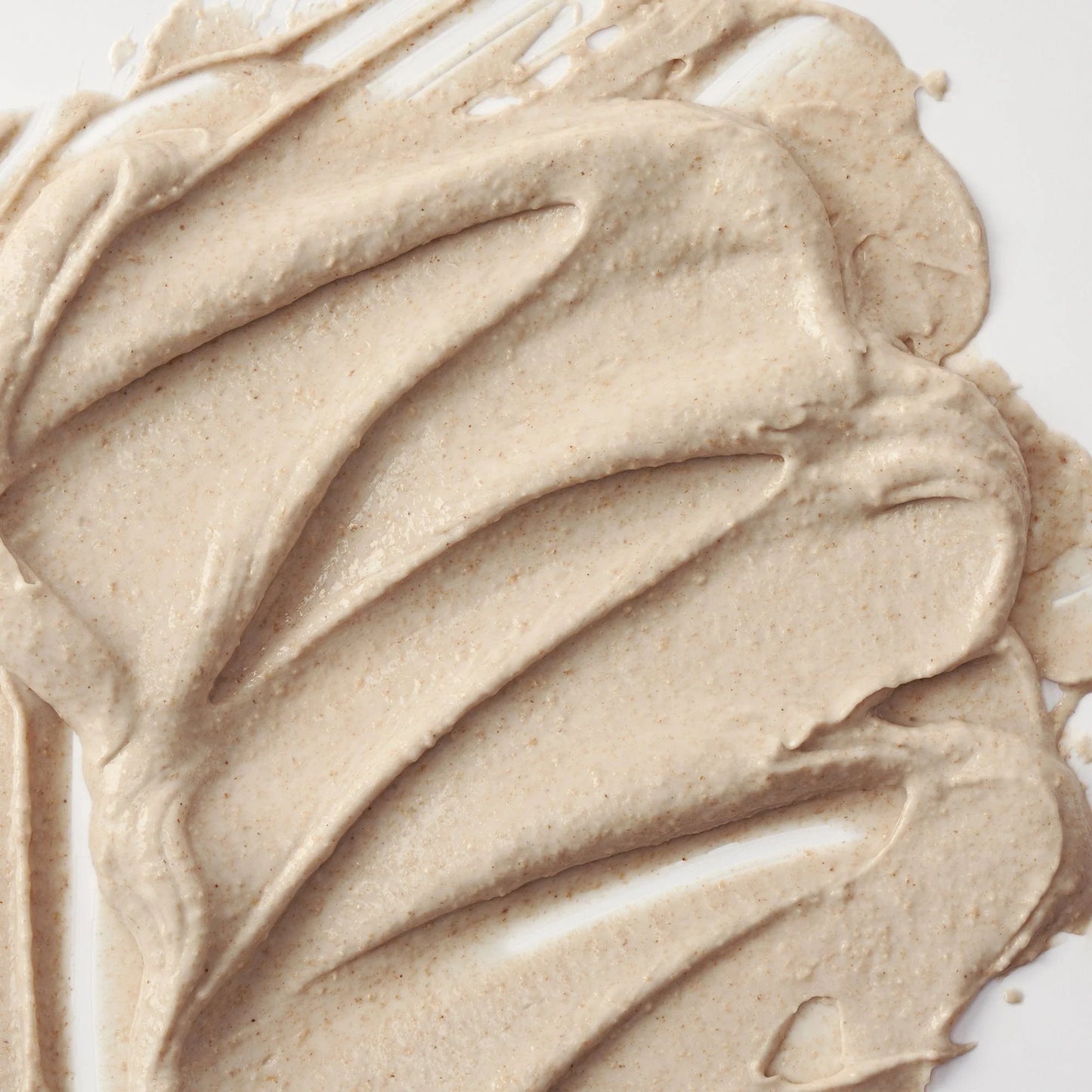 Nahaufnahme einer cremigen, beigefarbenen Textur, glatt auf einer Oberfläche verteilt.