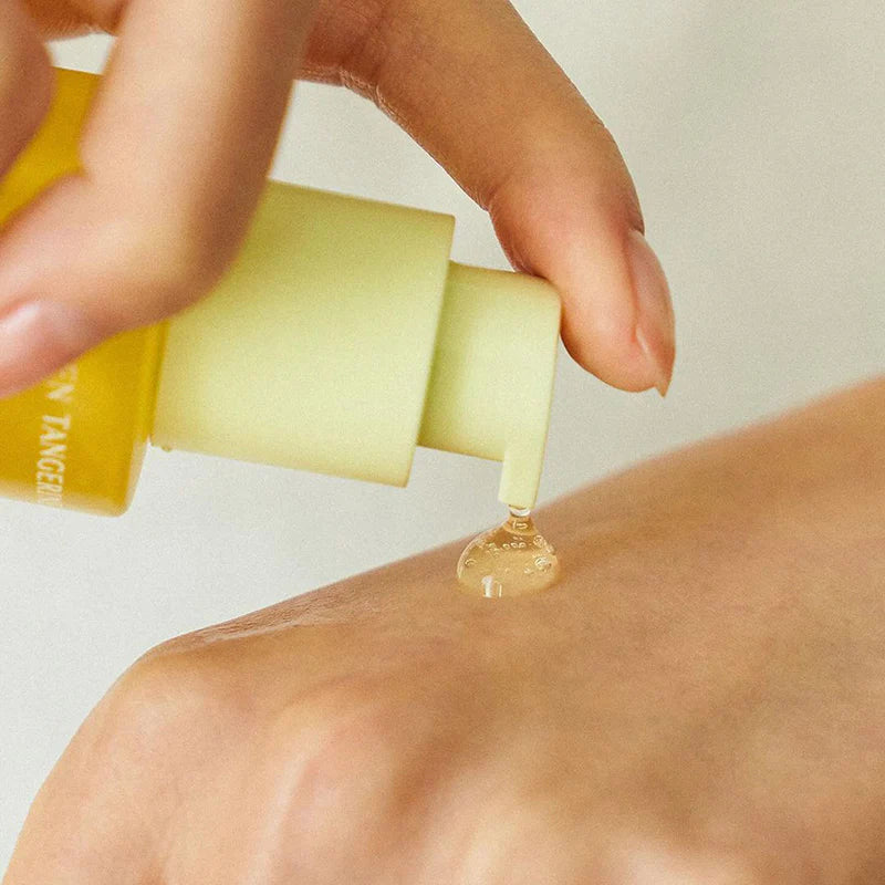 Gelber Pumpspender gibt einen Tropfen Serum auf eine Handfläche ab.