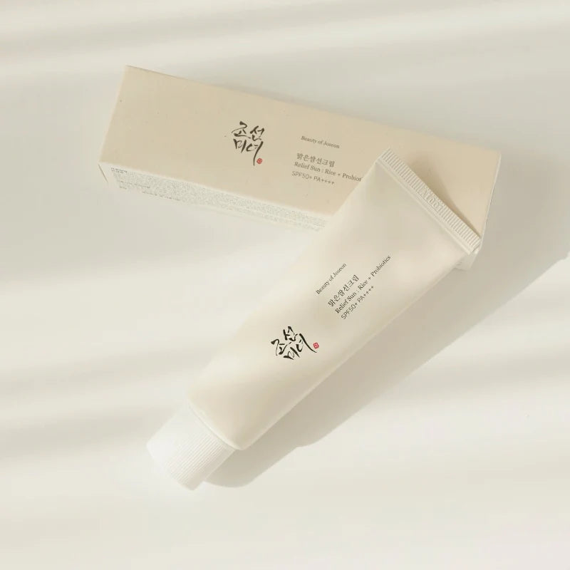 Tube Sonnencreme neben ihrer passenden Verpackung auf einem hellen, schattigen Hintergrund.