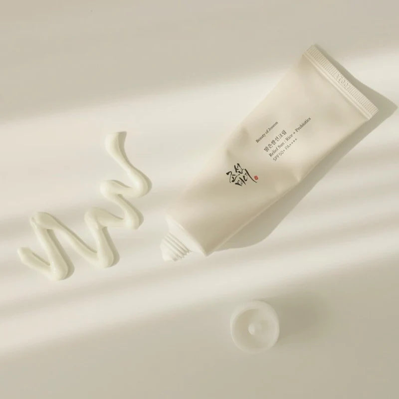 Tube Creme liegt auf einer hellen Oberfläche, mit einer geschwungenen Spur weißer Creme daneben. Die Kappe der Tube ist offen.