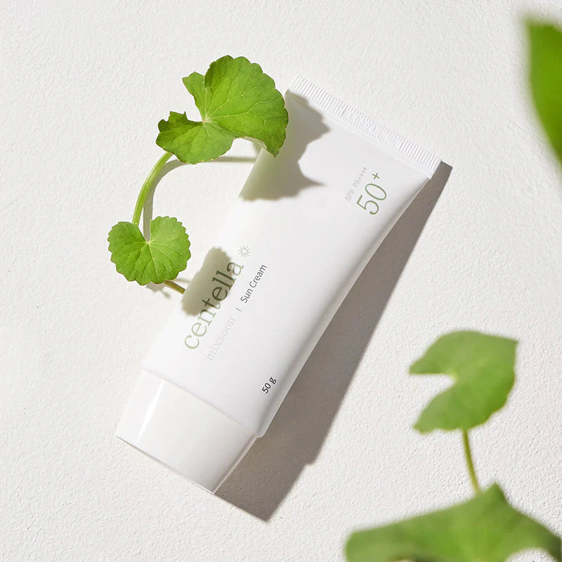 Tube der Sun Cream liegt auf hellem Hintergrund, dekoriert mit frischem Centella-Blatt.