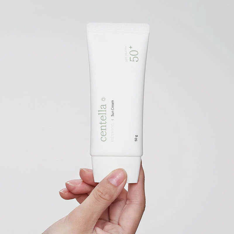 Hand hält Tube der Sun Cream vor weißem Hintergrund.