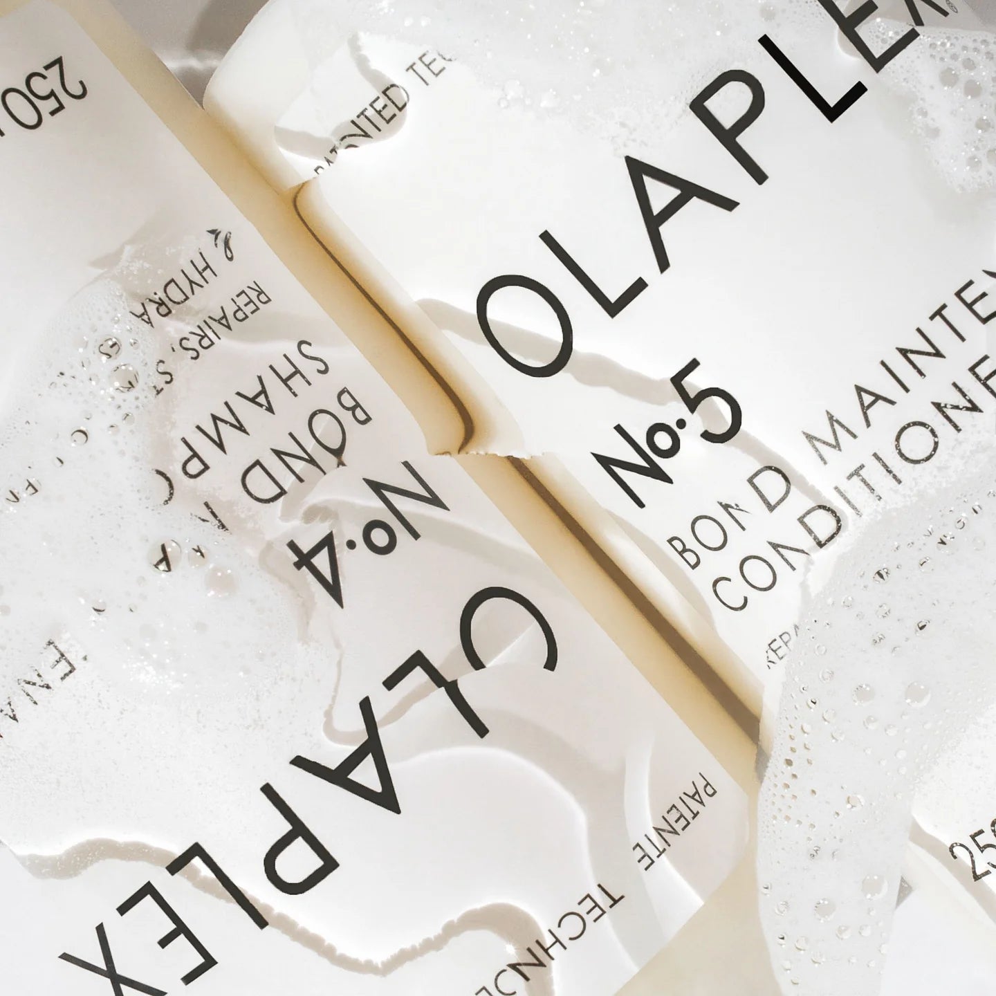 Zwei Flaschen Olaplex No.4 und No.5 mit Wasser benetzt.
