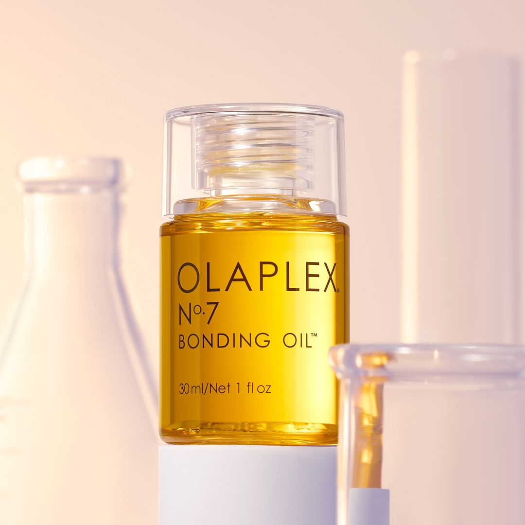 Eine Flasche Olaplex No. 7 Bonding Oil vor einem Hintergrund, der an ein Labor erinnert.