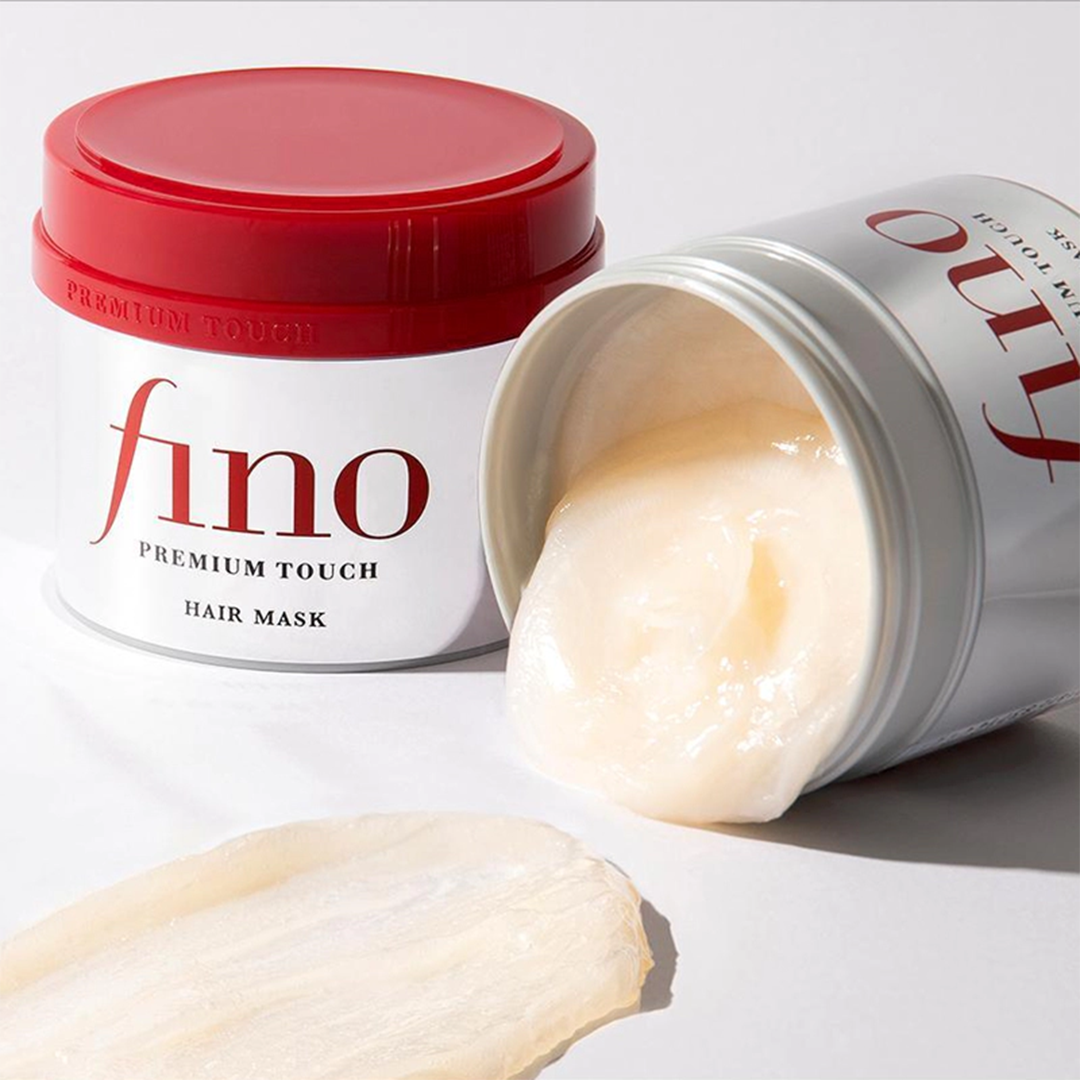Fino Hair Mask, liegend mit geöffneter Dose. Die cremige Maske fließt leicht heraus, mit einer Texturprobe daneben.