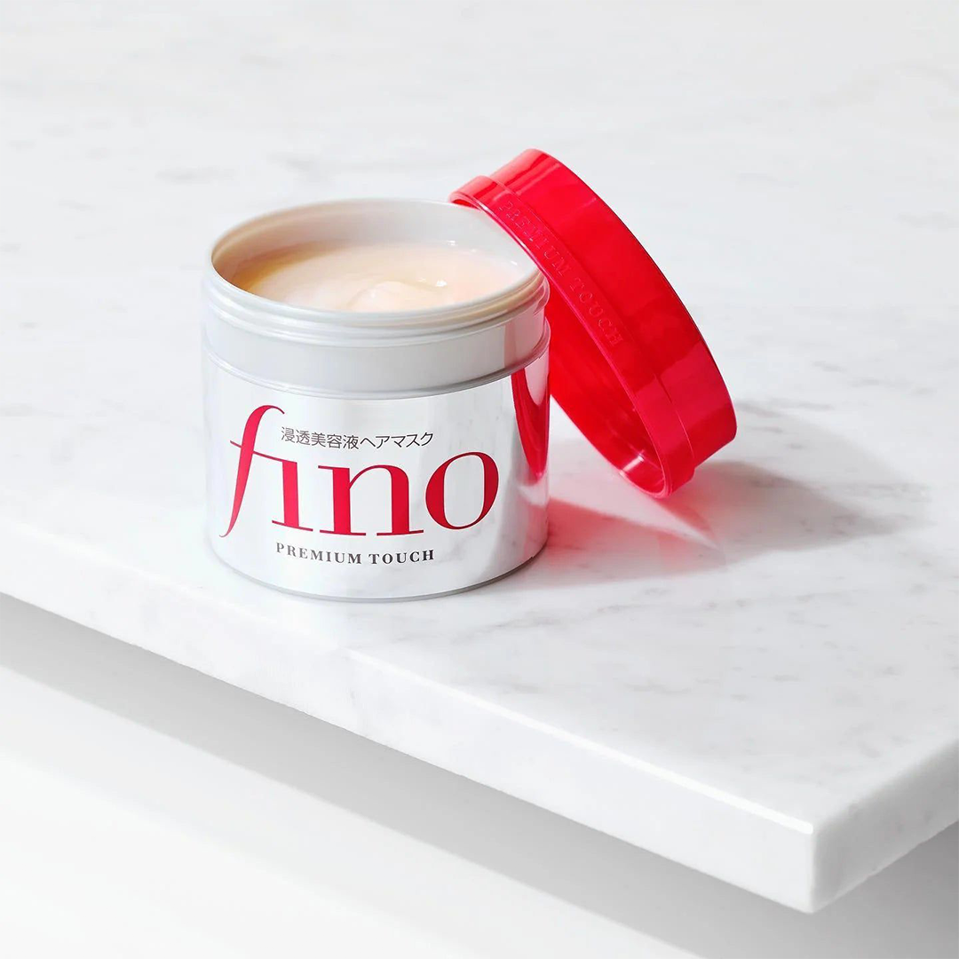 Geöffnete Dose der Fino Hair Mask auf einer Marmorplatte. Die cremige Textur ist sichtbar, der Deckel liegt daneben.