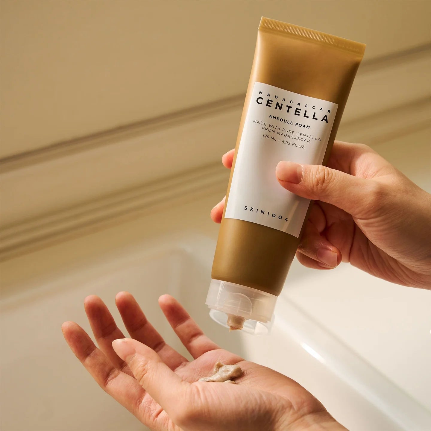 Goldene Tube, Creme wird in die Handfläche gedrückt.