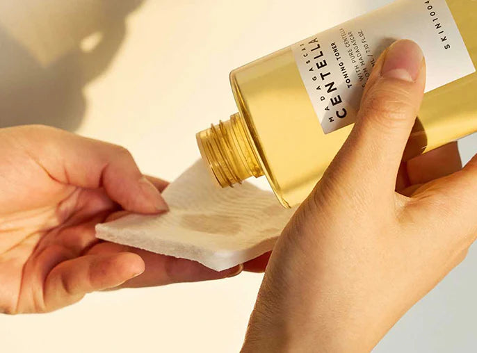 Hände gießen den Toner aus der Flasche auf ein Wattepad, beige Hintergrund.