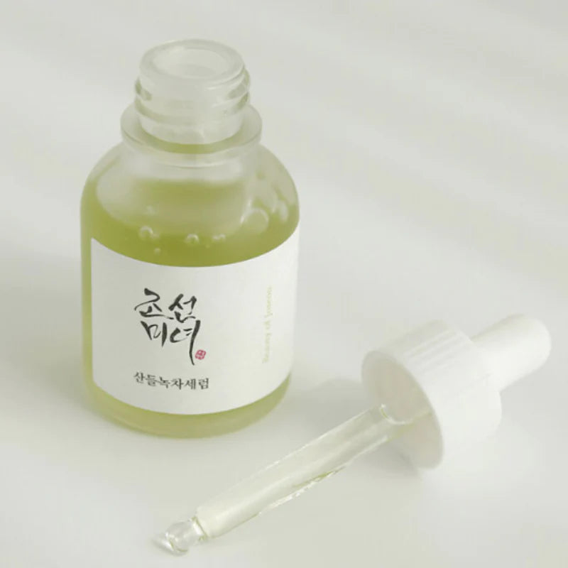Offene Glasflasche mit grünlicher Flüssigkeit, daneben liegt eine weiße Pipette mit etwas Serum.