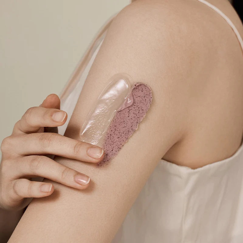 Person, die eine rosa-braune Maske auf ihren Arm aufträgt. Daneben ist eine transparente Schicht.