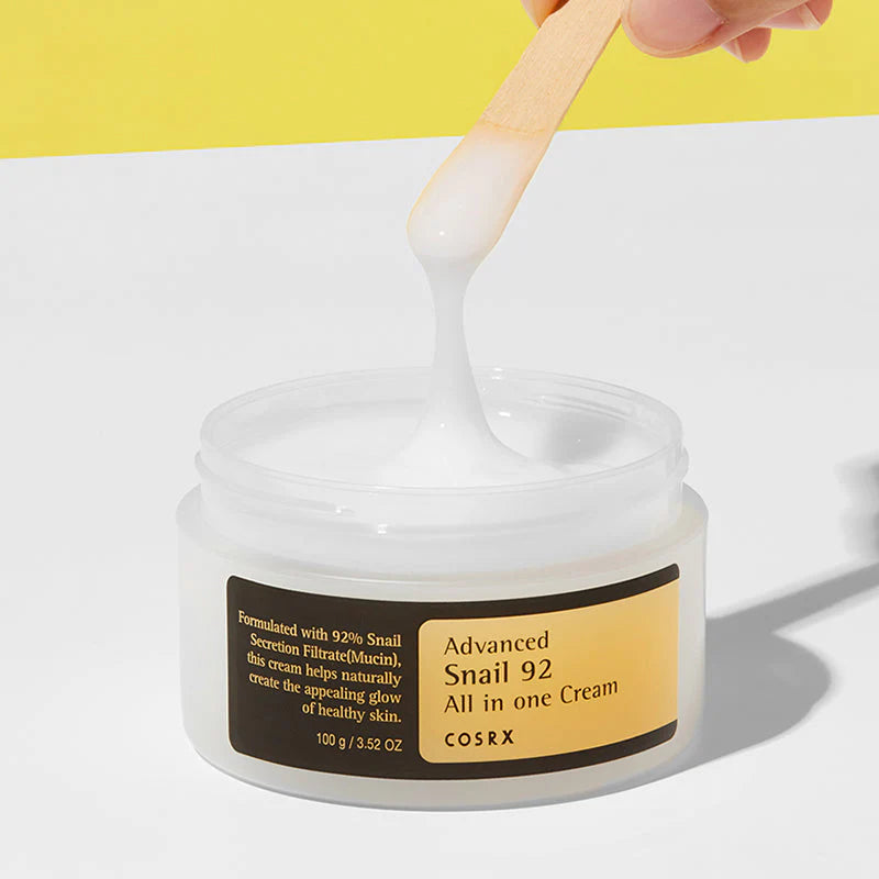 Eine offene Cremedose. Ein Spatel hebt die zähflüssige Creme heraus.