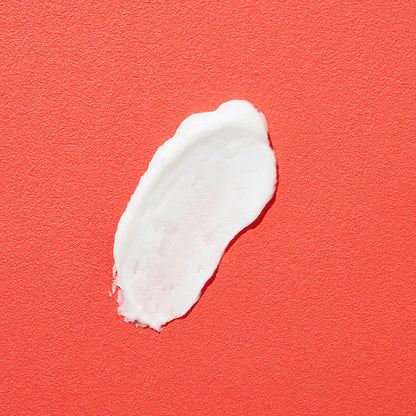 Weiße Creme wird auf rotem Hintergrund verstreichen.