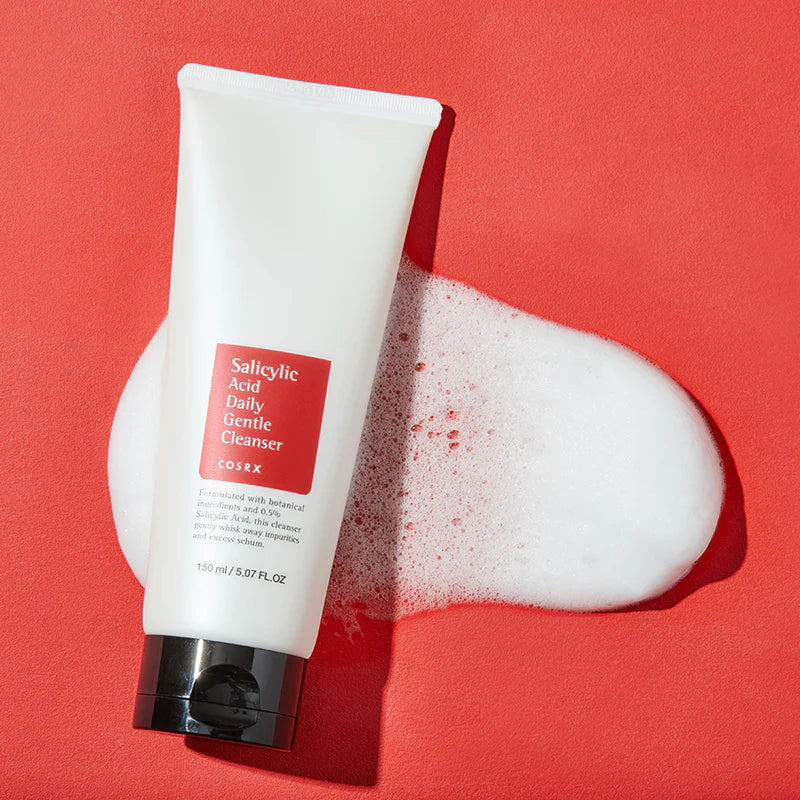 Tube des Cleansers liegt auf rotem Hintergrund, umgeben von Schaum.