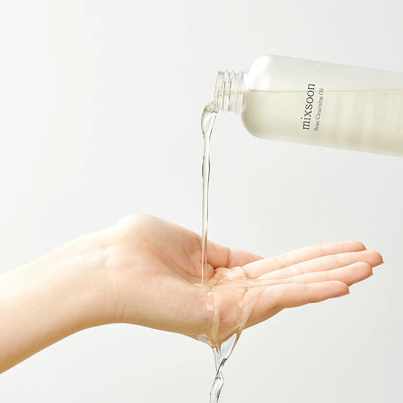 Öl wird aus der Flasche in die Hand gegossen, klare Flüssigkeit fließt herab.