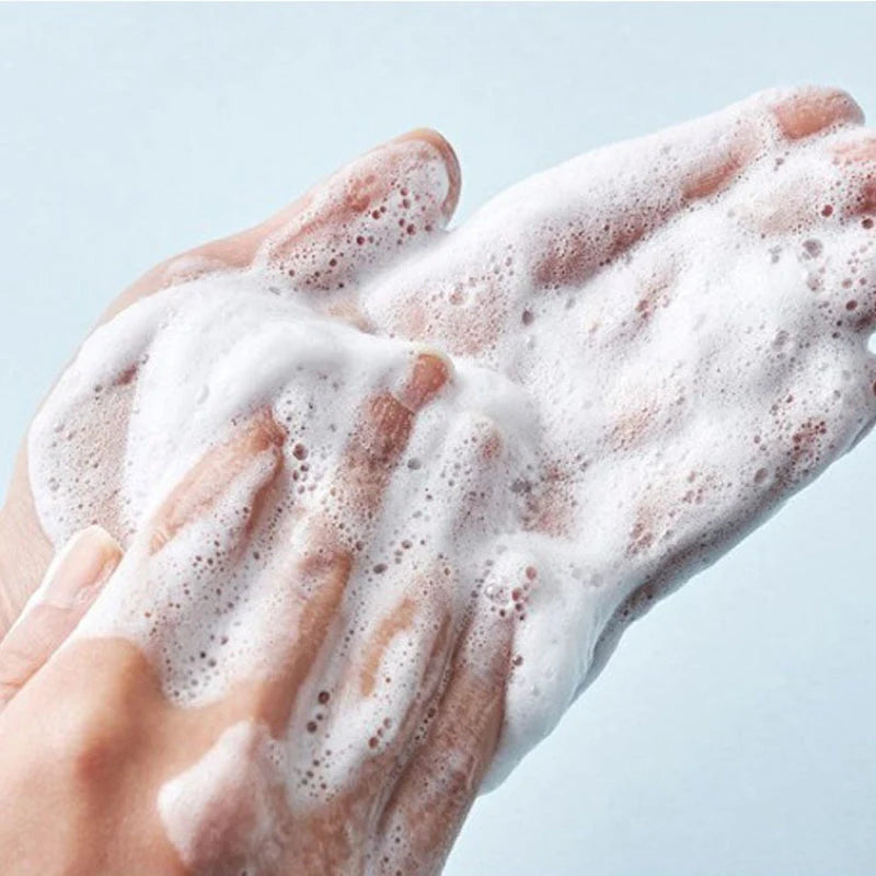 Nahaufnahme von aufgeschäumtem Cleanser in den Händen, zeigt die reinigende Textur.