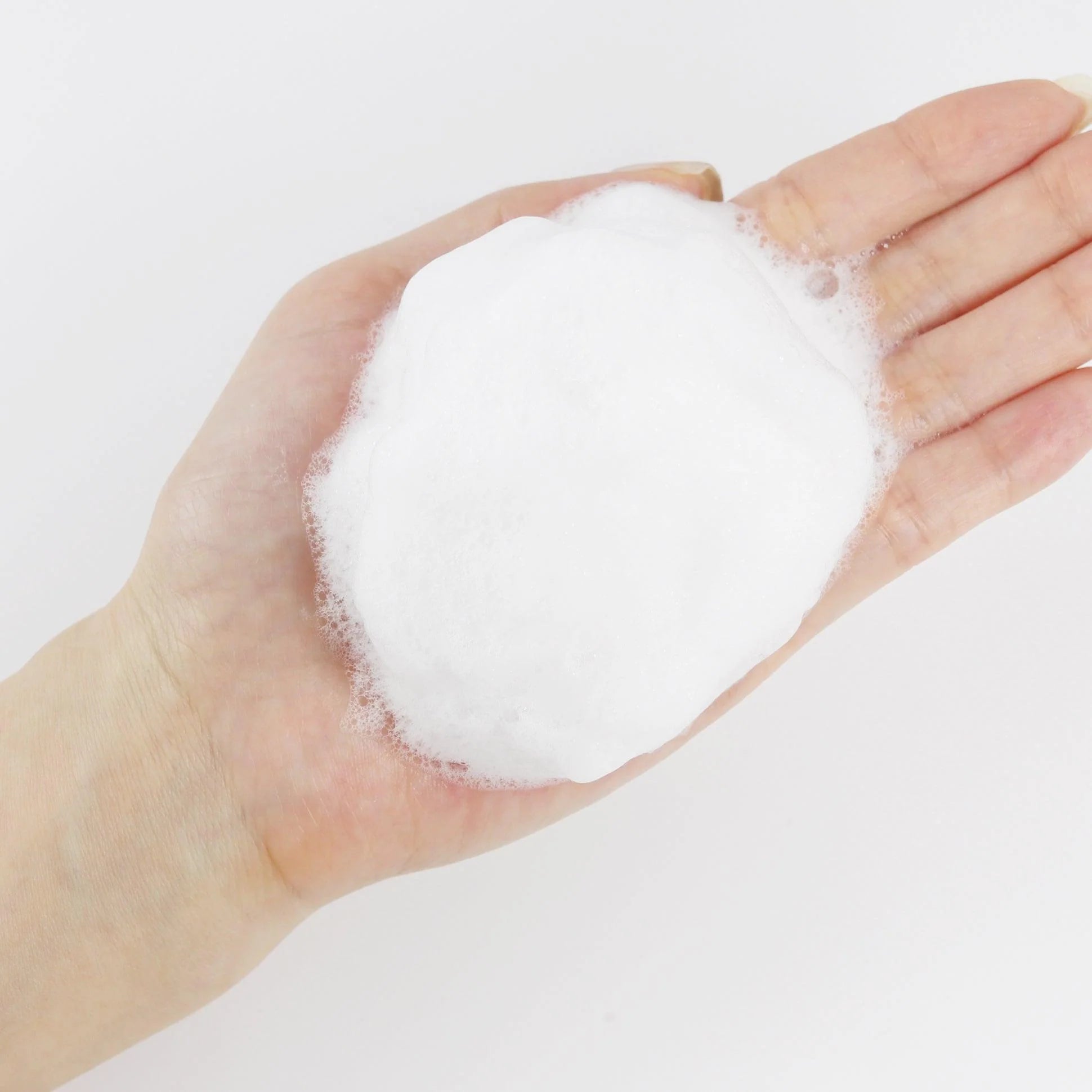 Aufgeschäumter Cleanser in der Hand, feiner, dichter Schaum für sanfte Reinigung.