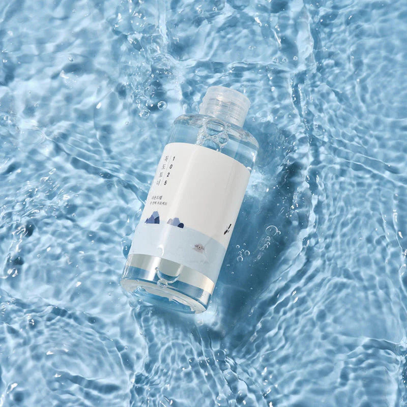 Flasche schwimmt in Wasser, wellenartige Reflexionen, betont Frische und Reinheit.