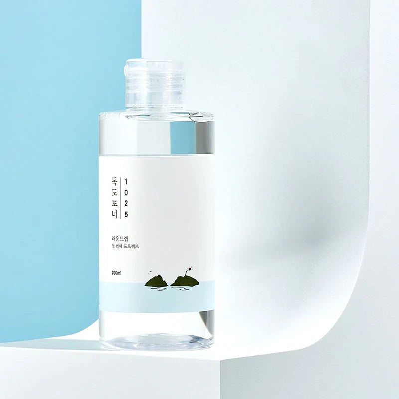 Flasche auf weißem Podest vor hellblauem Hintergrund, modern und minimalistisch präsentiert.