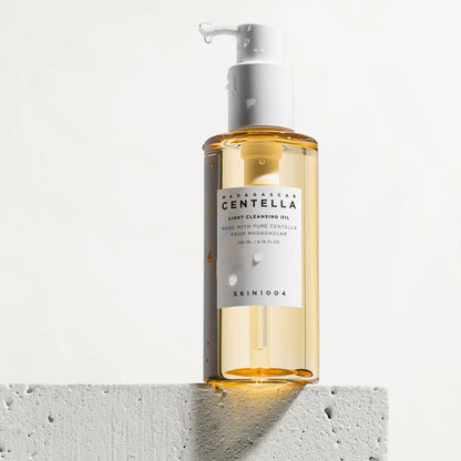 Eine nasse Flasche Cleansing Oil mit Wassertropfen auf weißem Hintergrund.