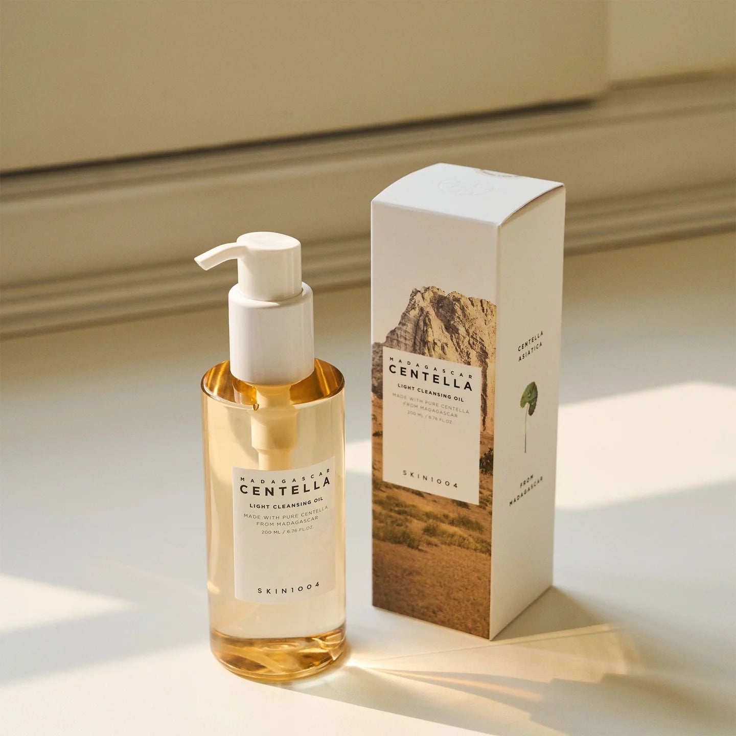 Cleansing Oil mit Verpackung, auf einem Tisch in warmem Sonnenlicht.