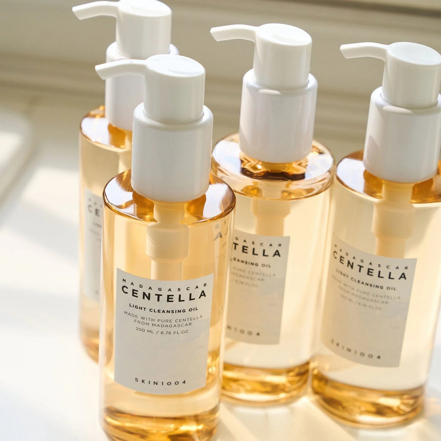 Vier Flaschen des Cleansing Oils stehen nebeneinander im Licht.