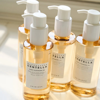 Vier Flaschen des Cleansing Oils stehen nebeneinander im Licht.