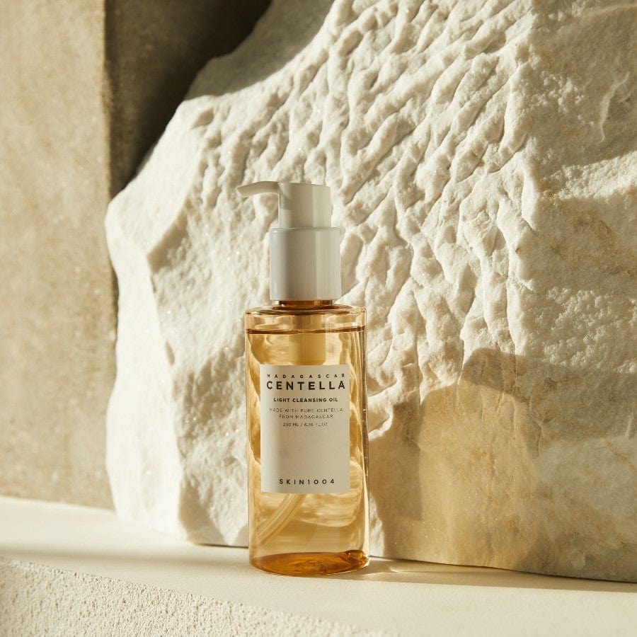 Eine Flasche Cleansing Oil, angestrahlt auf weißem Stein mit natürlicher Textur.